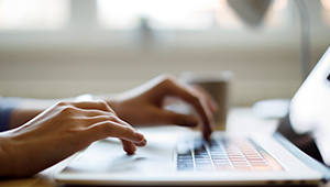 Image of a persona using a laptop to review Dexcom CGM FAQs